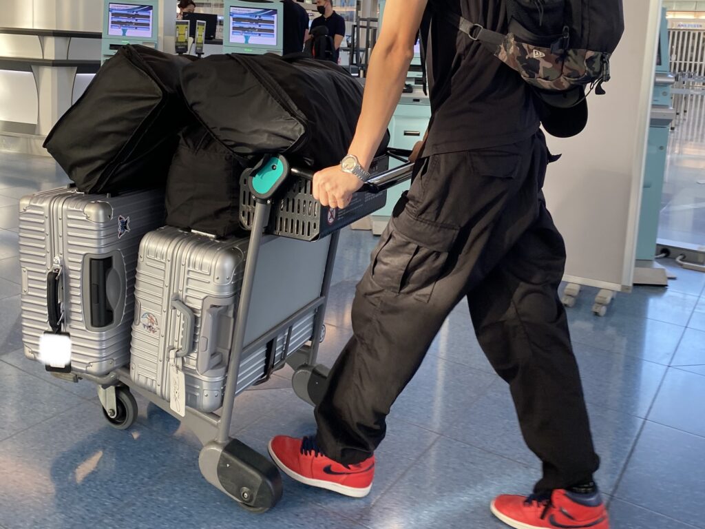 空港で荷物をカートに乗せて運んでいる写真
